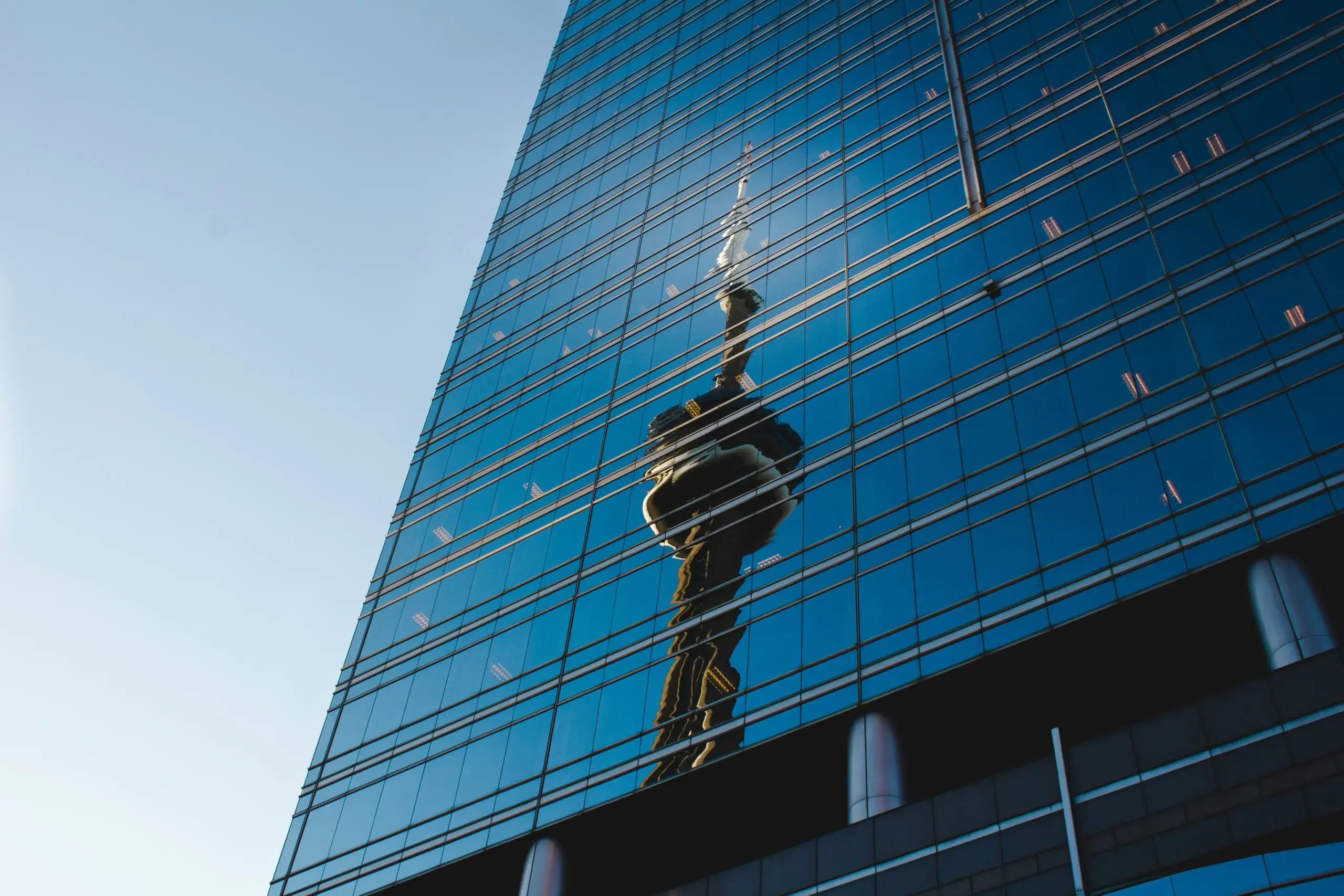 Glass building facade reflecting the CN Tower