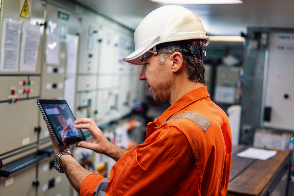 Technician reviewing a tablet beside industrial equipment controls.
